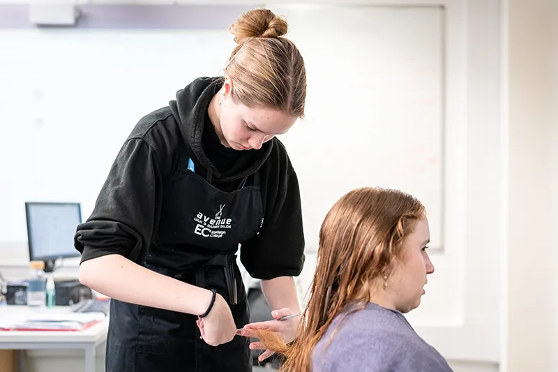 student cutting a persons hair in the salon