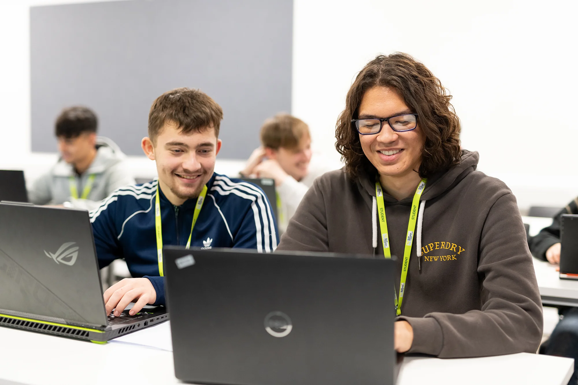 Two young men using laptops in a classroom