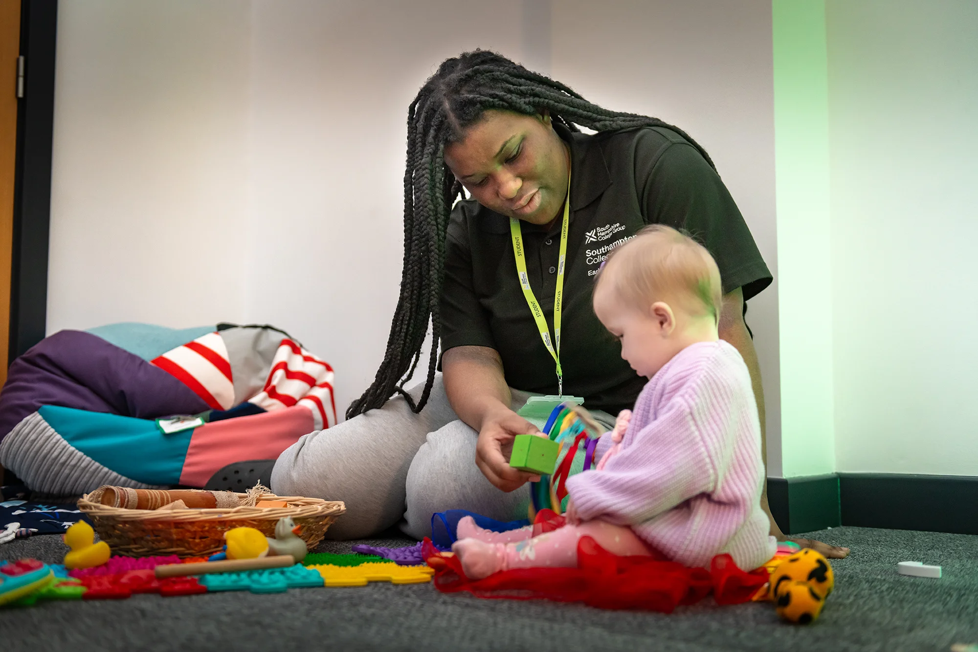 Student playing with a young child showing her toys 
in a nursery setting