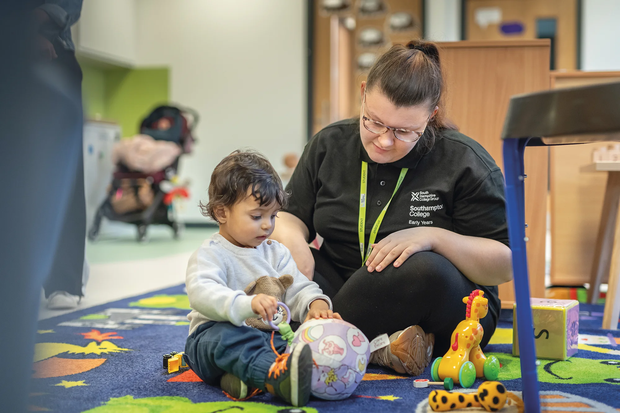 Student showing a young child blocks in a nursery 
setting