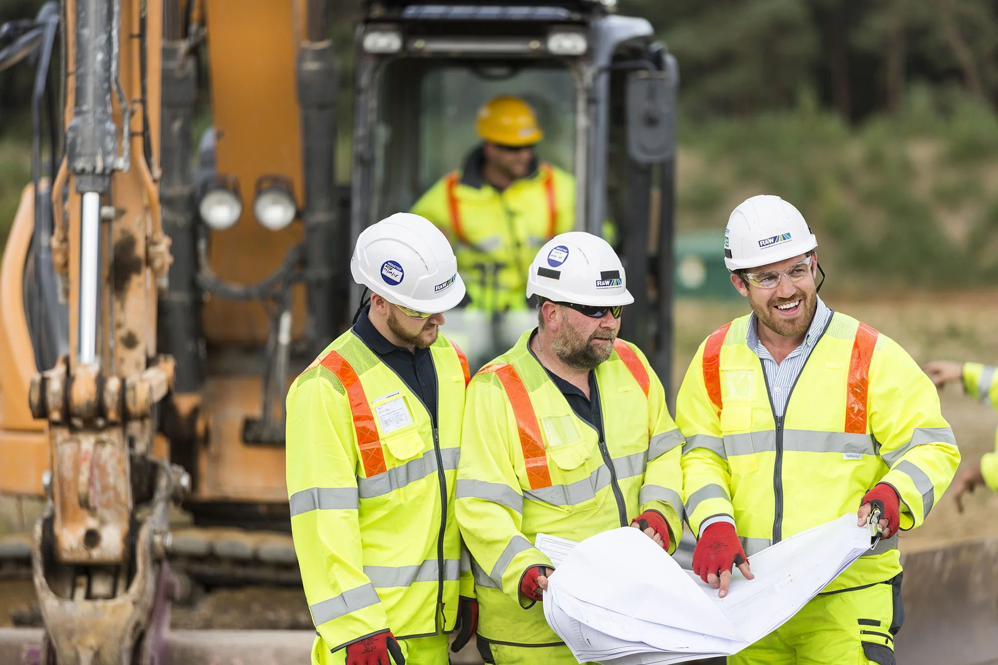 Three workers in in protective equipment on a building site looking at plans