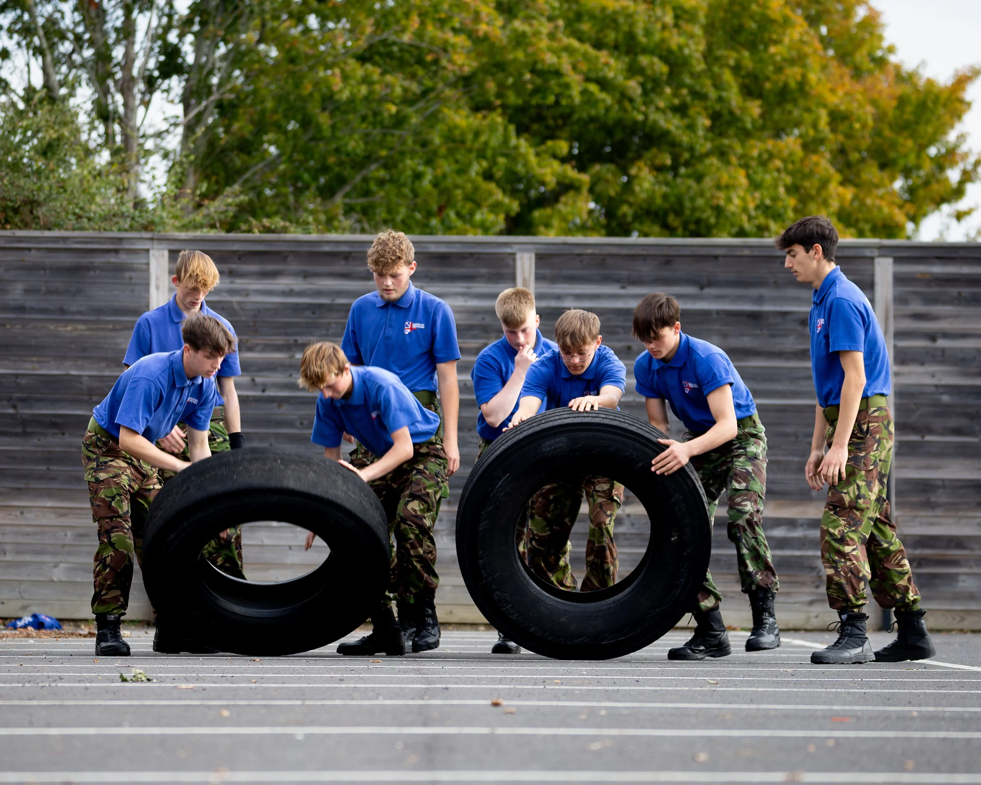 Cadets in uniform moving giant tyres