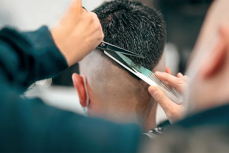 student cutting a persons hair in the salon