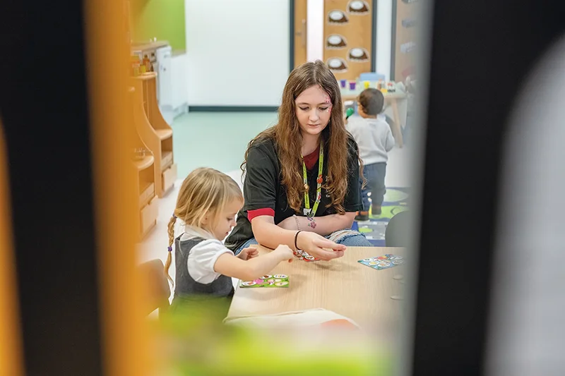 Student playing with a young child showing her toys 
in a nursery setting