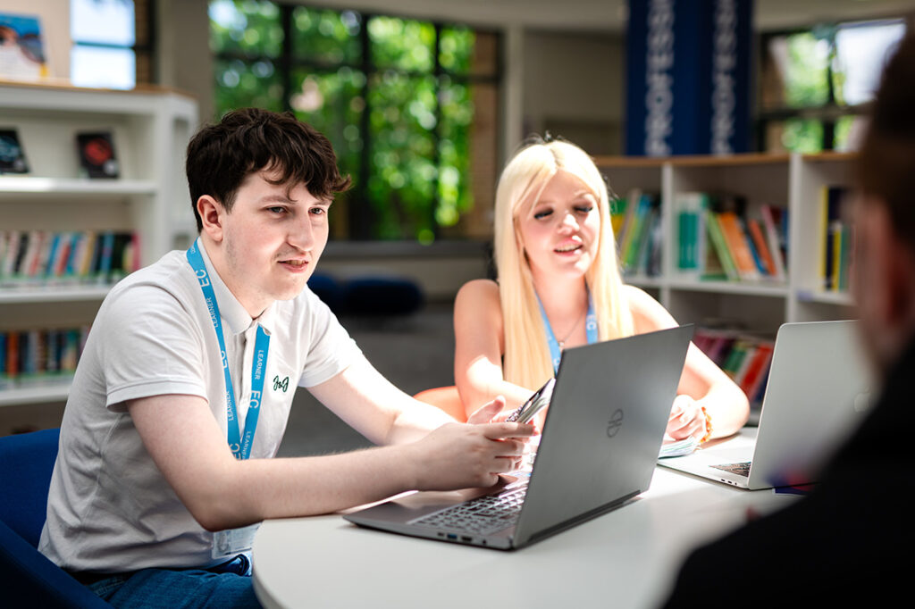 Student talking with laptops on table